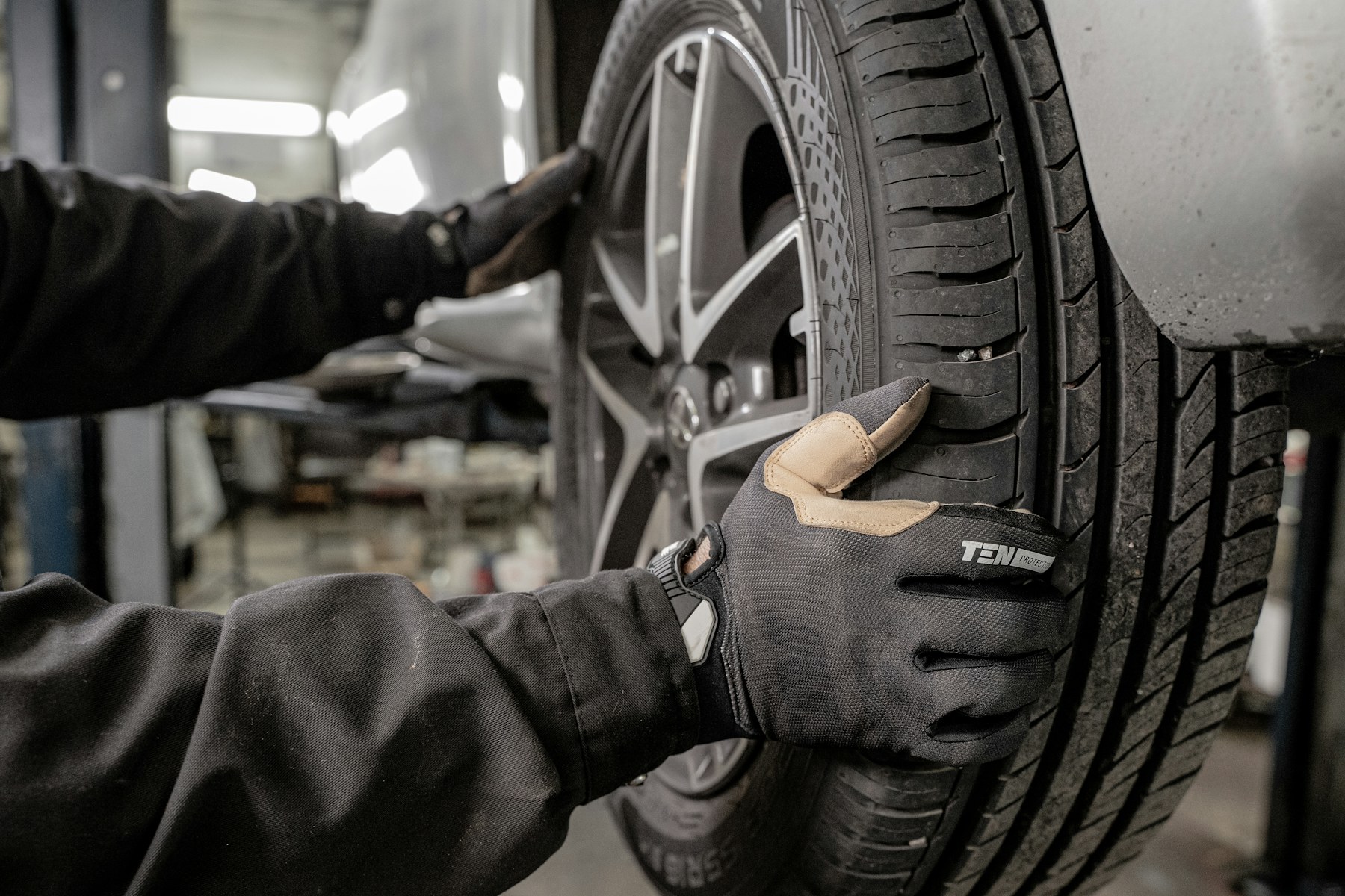 Monteur met handschoenen zet een wiel terug op de wagen