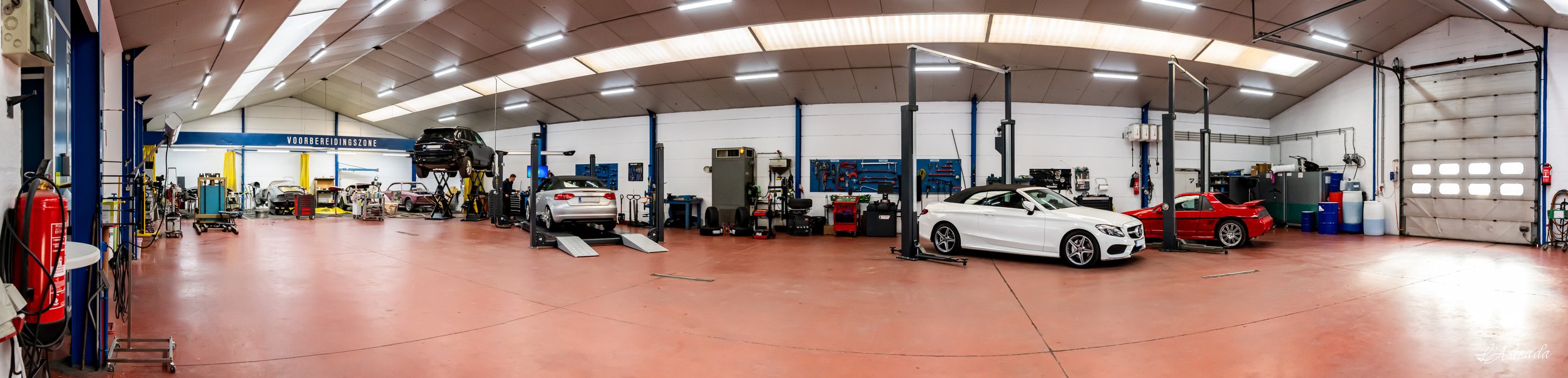 Panorama van de werkplaats van Car Care Peeters: hefbruggen, wagens en werkposten